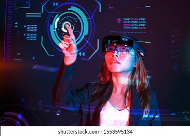 Young asian girl try augmented and virtural reality glasses hololens in the lab room. Mixed reality future technology concept.