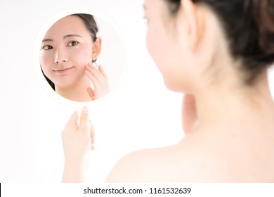 Young asian girl using a hand mirror. Skin care concept.