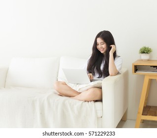 Young Asian Girl Using Laptop On The Couch With Smiley Face