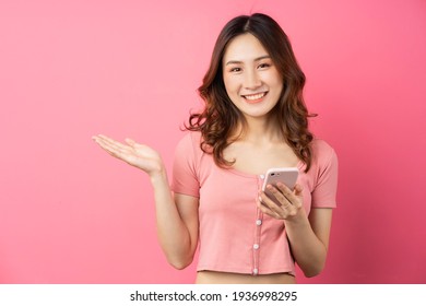 Young Asian Girl Using The Phone On Pink Background