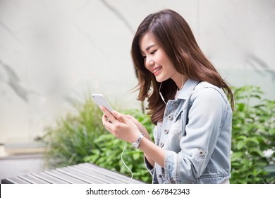 Young Asian Girl Using Smart Phone In The Garden