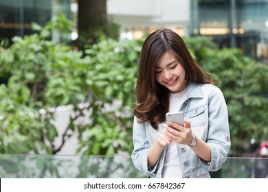 Young Asian Girl Using Smart Phone In The Garden