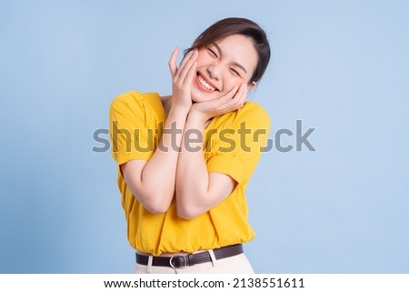 Young Asian girl wearing yellow shirt posing on blue background