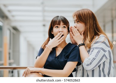 Young Asian Girl Whispering Gossip Or Secret To Her Friend With Surprise Face