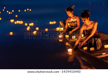 Young asian girls floating lanterns in the lake. The festival may originate from an ancient ritual praying respect to the water spirits.