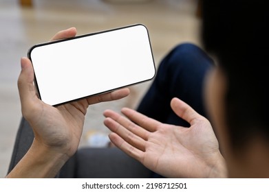 Young Asian Guy Watching Football Match Or Game Live-streaming On His Smartphone. Dissatisfaction Or Failure Gesture Expression. Phone White Screen Mockup. Close-up Image