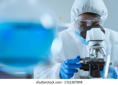 Young Asian Handsome Man Scientist Adjust Focus And Use Microscope To Looking Biochemical Cell In Laboratory. Doctor And Scientist Work In Laboratory Pandemic Of Corona Virus, COVID19 Concept