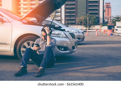 Young asian handsome man sitting by the Broken Down car and using smart phone for help - Powered by Shutterstock