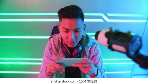 Young Asian Handsome Pro Gamer Play Online Mobile Game With Smart Phone And Having Live Stream