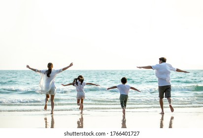 Young Asian happy family parent with child girl and boy running and having fun together on the beach in sunny summer day. Smiling father and mother with two kid enjoy summer lifestyle travel vacation. - Powered by Shutterstock