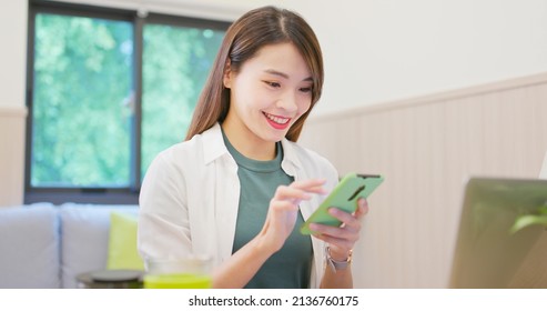 Young Asian Happy Smiling Woman Is Using Mobile Phone And Laptop Computer At Home