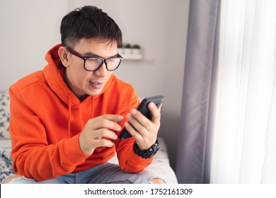 Young Asian happy while using smartphone chatting and making facetime video calling, lockdown situation. Social distancing concept. Bangkok Thailand