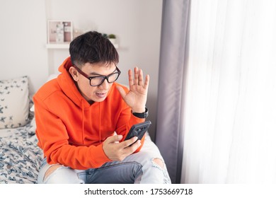 Young Asian happy while using smartphone making facetime video calling, lockdown situation. Social distancing concept. Bangkok Thailand