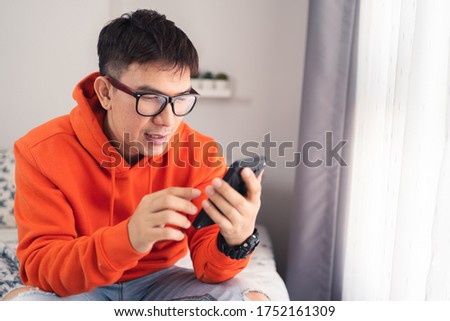 Young Asian happy while using smartphone chatting and making facetime video calling, lockdown situation. Social distancing concept. Bangkok Thailand