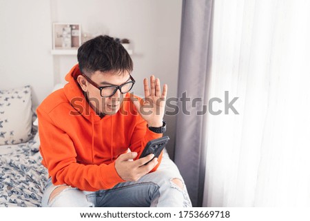Young Asian happy while using smartphone making facetime video calling, lockdown situation. Social distancing concept. Bangkok Thailand