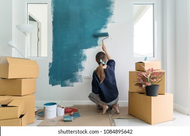 Young Asian Happy Woman Painting Interior Wall With Paint Roller In New House, Home Decoration Concept