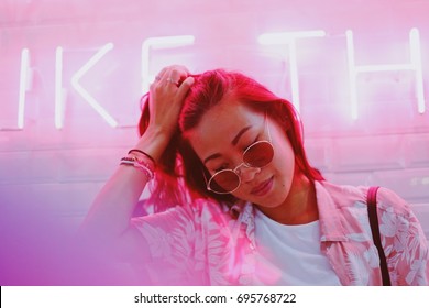 Young Asian Hipster Millennials Woman In Street Style Fashion Summer Concept And Wearing Sunglasses In Pink Neon Light