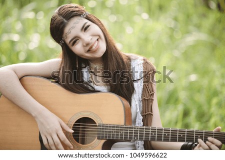 Young Asian Hipster playing guitar in the park