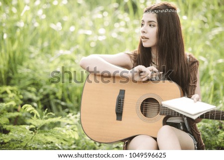 Young Asian Hipster playing guitar in the park