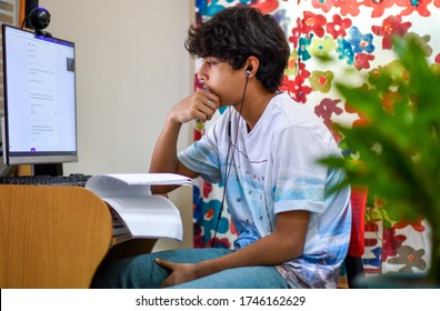 Young asian , Indian boy student virtual study at home. He using computer and learning online during COVID-19 pandemic.