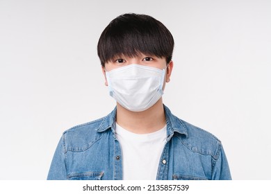 Young asian korean boy man student freelancer in denim shirt and protective face mask against Coronavirus Covid19 looking at the camera isolated on white background. Pandemic concept