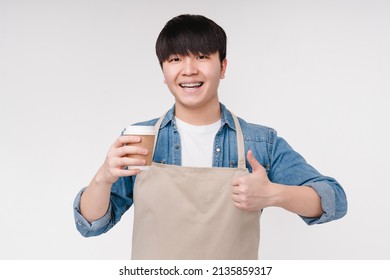 Young Asian Korean Man Barista Coffee Shop Assistant Holding Hot Beverage Decaf Coffee Tea Showing Thumb Up Isolated On White Background