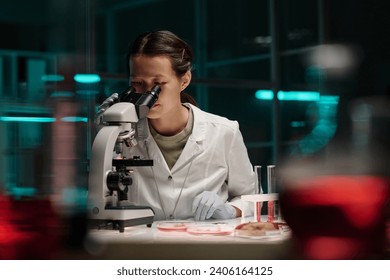 Young asian lab assistant looking through microscope conducting scientific research - Powered by Shutterstock - Get 15% off with code: PIKWIZARD15