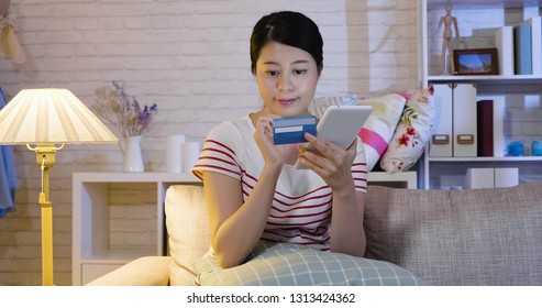young asian lady sitting on couch with tablet pc and credit card in hand. woman entering password account on internet web site buying thing bargain price. girl hobby shopping online love fashion - Shutterstock ID 1313424362
