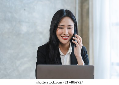 Young Asian Lawyer Woman Professional In A Suit Sitting At A Desk In Her Office. She Looks, Happy, Hopeful And Confident About Her Future.