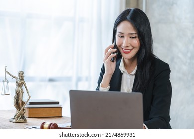 Young Asian Lawyer Woman Professional In A Suit Sitting At A Desk In Her Office. She Looks, Happy, Hopeful And Confident About Her Future.