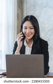 Young Asian Lawyer Woman Professional In A Suit Sitting At A Desk In Her Office. She Looks, Happy, Hopeful And Confident About Her Future.