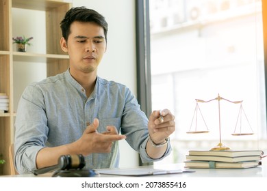 Young Asian Lawyer Working On Financial Audit And Client Support While Working Hard In The Office. Delegate Legal Concept Litigation With Hammers And Scales Placed In Front Of You.