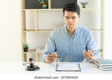 Young Asian Lawyer Working On Financial Audit And Client Support While Working Hard In The Office. Delegate Legal Concept Litigation With Hammers And Scales Placed In Front Of You.