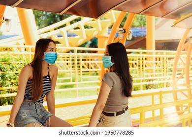 Young Asian LGBT Couples Travel To Theme Parks Together, Wear Face Masks, And Chat Apart At Roller Coaster Ride Stations To Ensure Safety And Spacing During The Covid-19 Outbreak To Prevent Infection.