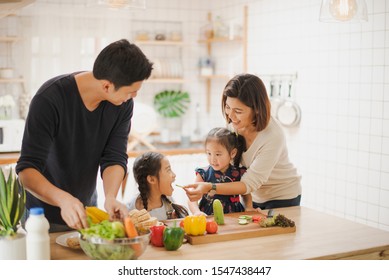 Young Asian love family are preparing the breakfast, sandwich vegetable on table in the kitchen which Excited smiling and felling happy. parent teach daughter to cooking food on the day at home. 