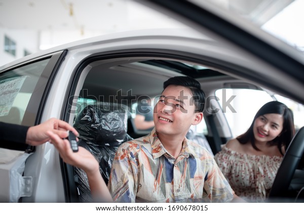 Young Asian lovers are happy to buy\
a new car at the dealer and buy a car with the car\
dealer.
