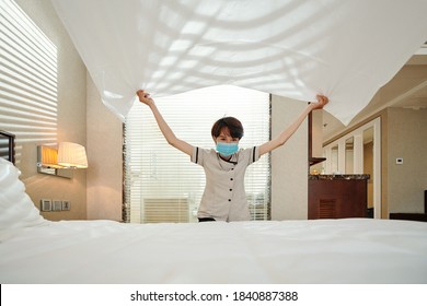 Young Asian Maid In Medical Mask Changing Sheet On Bed In Hotel Room