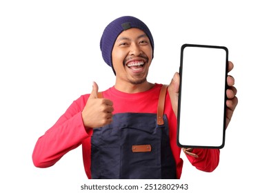 A young Asian male barista wearing a navy apron, red long-sleeve shirt, and beanie, excitedly showing a smartphone with a blank white screen to the camera, isolated on a white background - Powered by Shutterstock