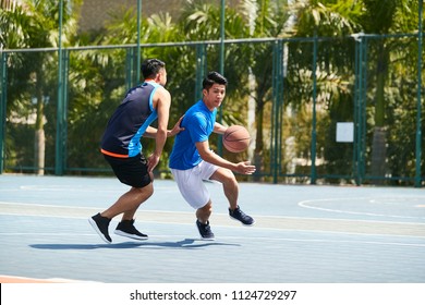 Young Asian Male Basketball Player Playing One-on-one On Outdoor Court.