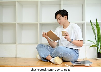 A young Asian male in casual suit sitting in cafe co-working space, sipping coffee while reading a book. Hobby and leisure concept - Powered by Shutterstock