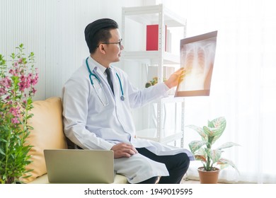 Young Asian Male Doctor Exam X-ray Film Lung In Clinic. Radiologist Analyzing The Results And Recording The Information On Laptop Computer In  Hospital Lab. Concept Medical Consultation, Health Care