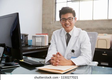 Young Asian Male Doctor Sitting At Desk, Portrait