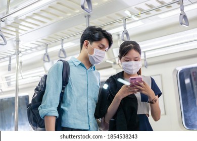 Young Asian male and female passenger in medical face mask using or playing smartphone in public metro subway. new normal lifestyle during Covid-19. people go to work or travel concept - Shutterstock ID 1854538243
