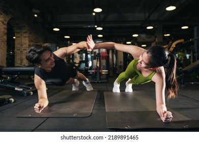 Young Asian Male And Female Planking Exercise In Fitness Gym For Building A Beautiful Slim Body. Professional Trainer Coach Helping Young Woman Exercising In The Sport Gym.