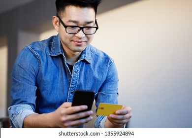 Young Asian Male Holding Hands Credit Card And Mobile Phone. Technology, Internet Banking, E-commerce And Online Shopping