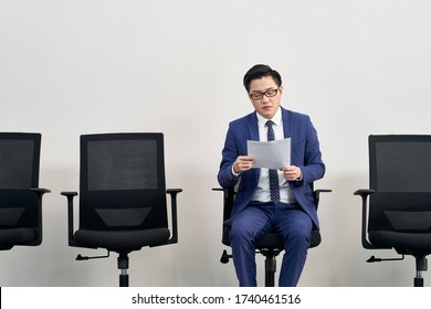 young asian male job seeker preparing for interview while waiting in line