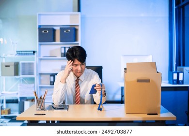 Young Asian male professional packing office belongings in a box, representing themes of resignation, new job, or relocation. Office, job, career change - Powered by Shutterstock