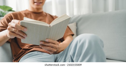 Young Asian Male Reading A Book In Sofa Relaxation At Home Concept.