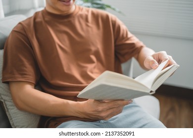 Young Asian Male Reading A Book In Sofa Relaxation At Home Concept.