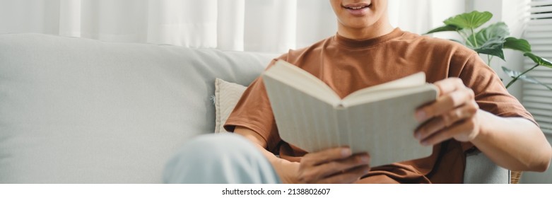 Young Asian Male Reading A Book In Sofa Relaxation At Home Concept.